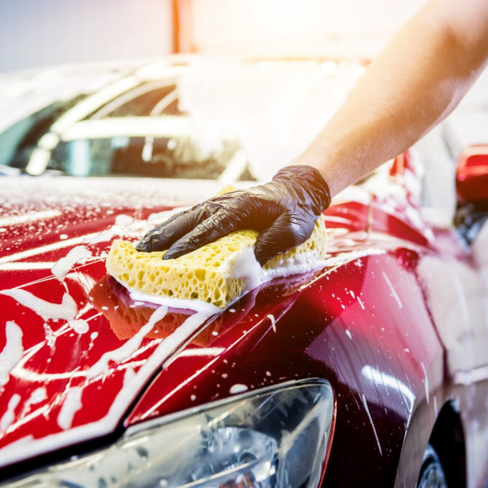 Worker,Washing,Red,Car,With,Sponge,On,A,Car,Wash