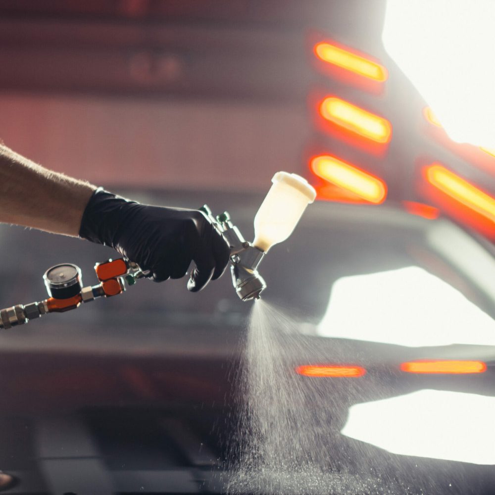 man die een spraycoating laag toepast op een wagen
